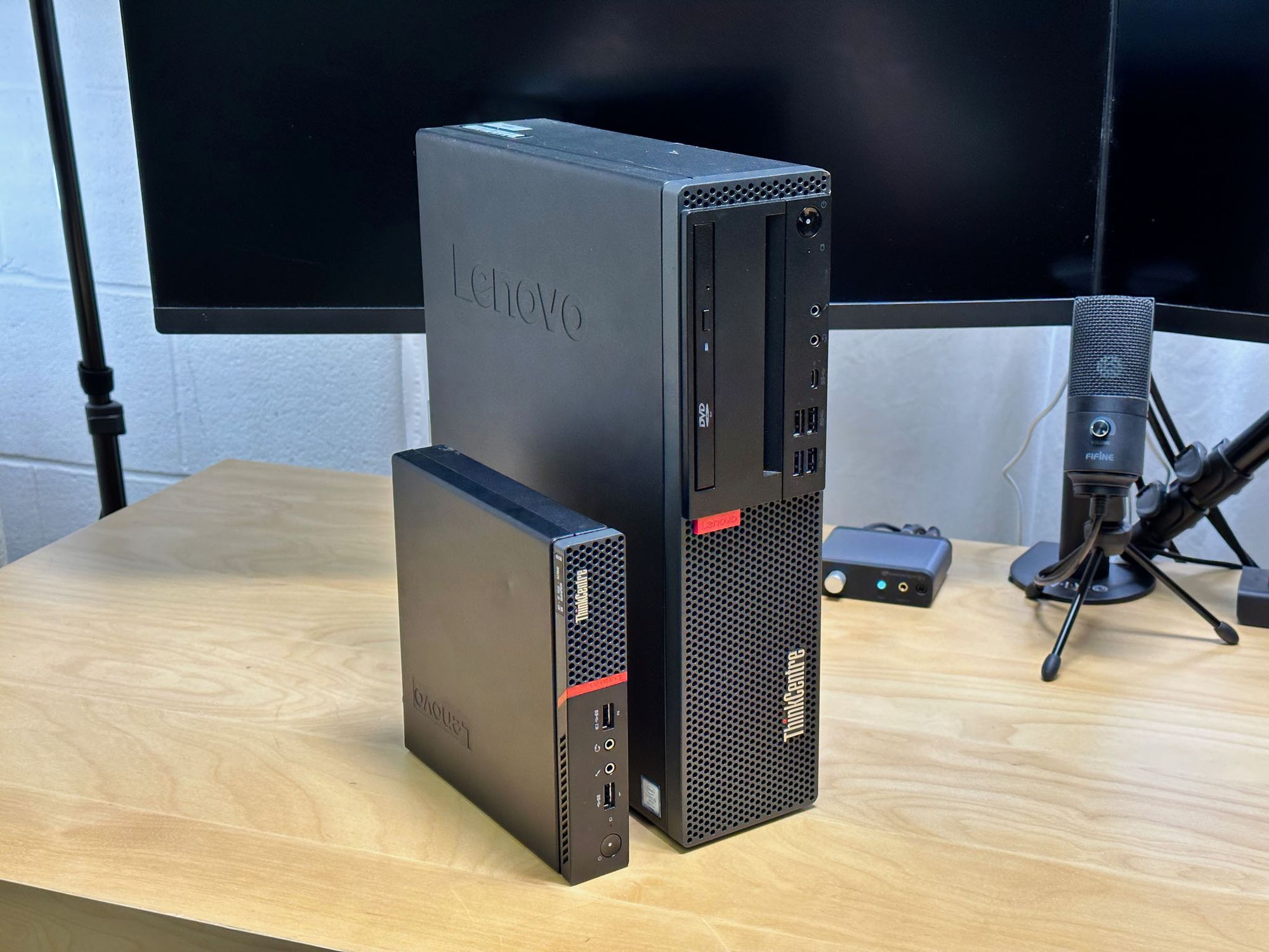 Two Lenovo ThinkCentre desktop computers standing vertically on a desk